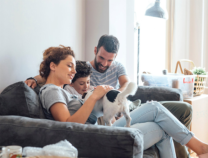 A young family sitting on a sofa in their new home